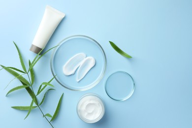 Photo of Petri dishes with cosmetic product and leaves on light blue background, flat lay. Space for text