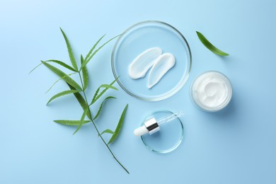 Photo of Petri dishes with cosmetic product, pipette and leaves on light blue background, flat lay