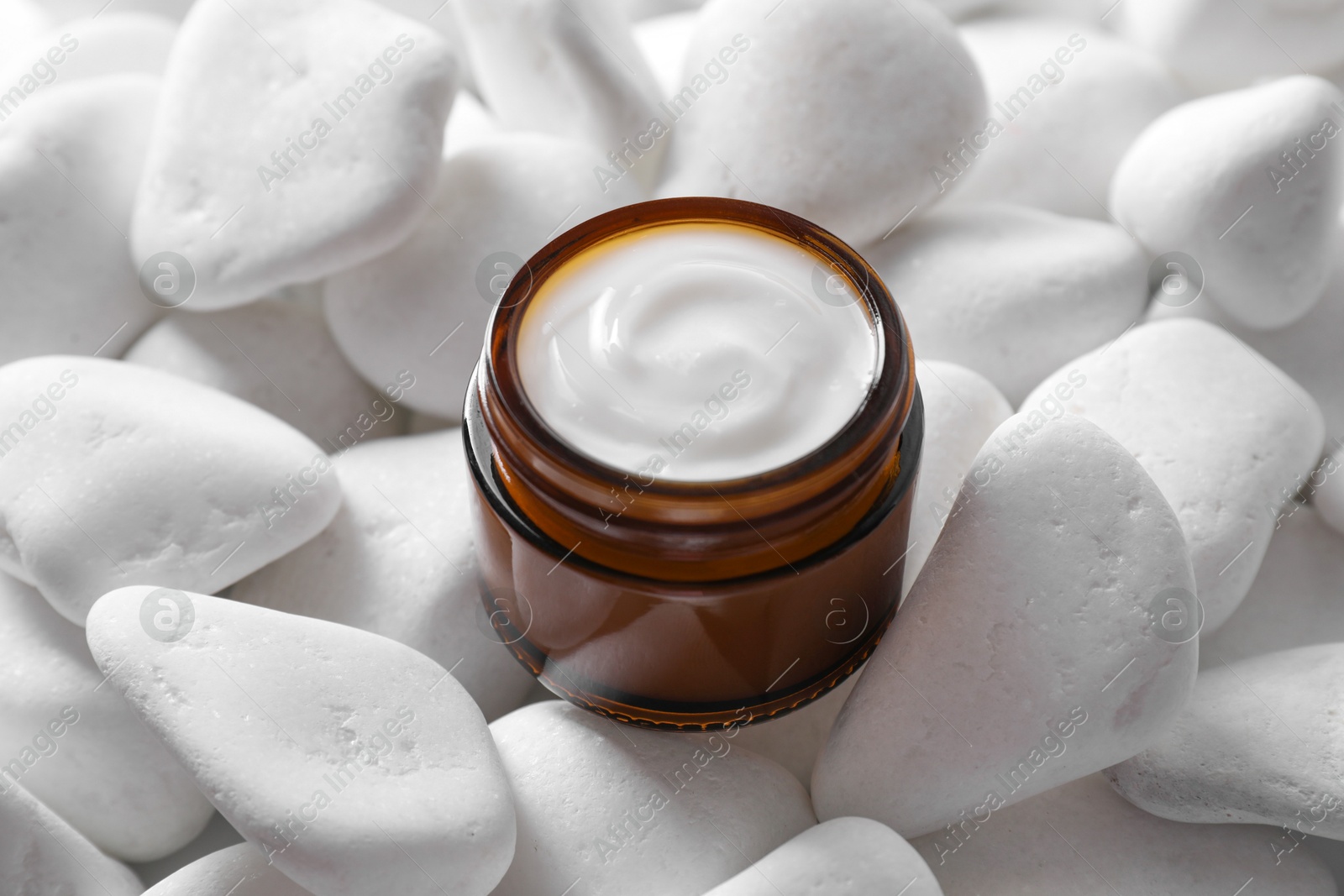 Photo of Face cream in jar on white stones. Cosmetic product