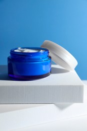 Photo of Stylish presentation of face cream in jar against light blue background