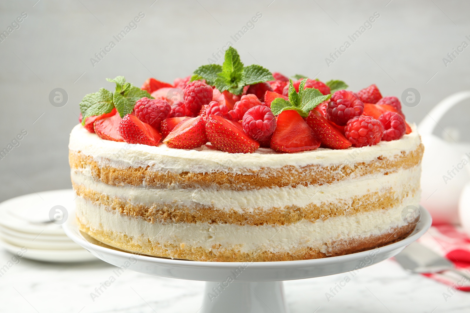 Photo of Tasty sponge cake with fresh berries and mint on white table, closeup