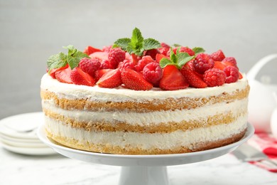 Photo of Tasty sponge cake with fresh berries and mint on white table, closeup