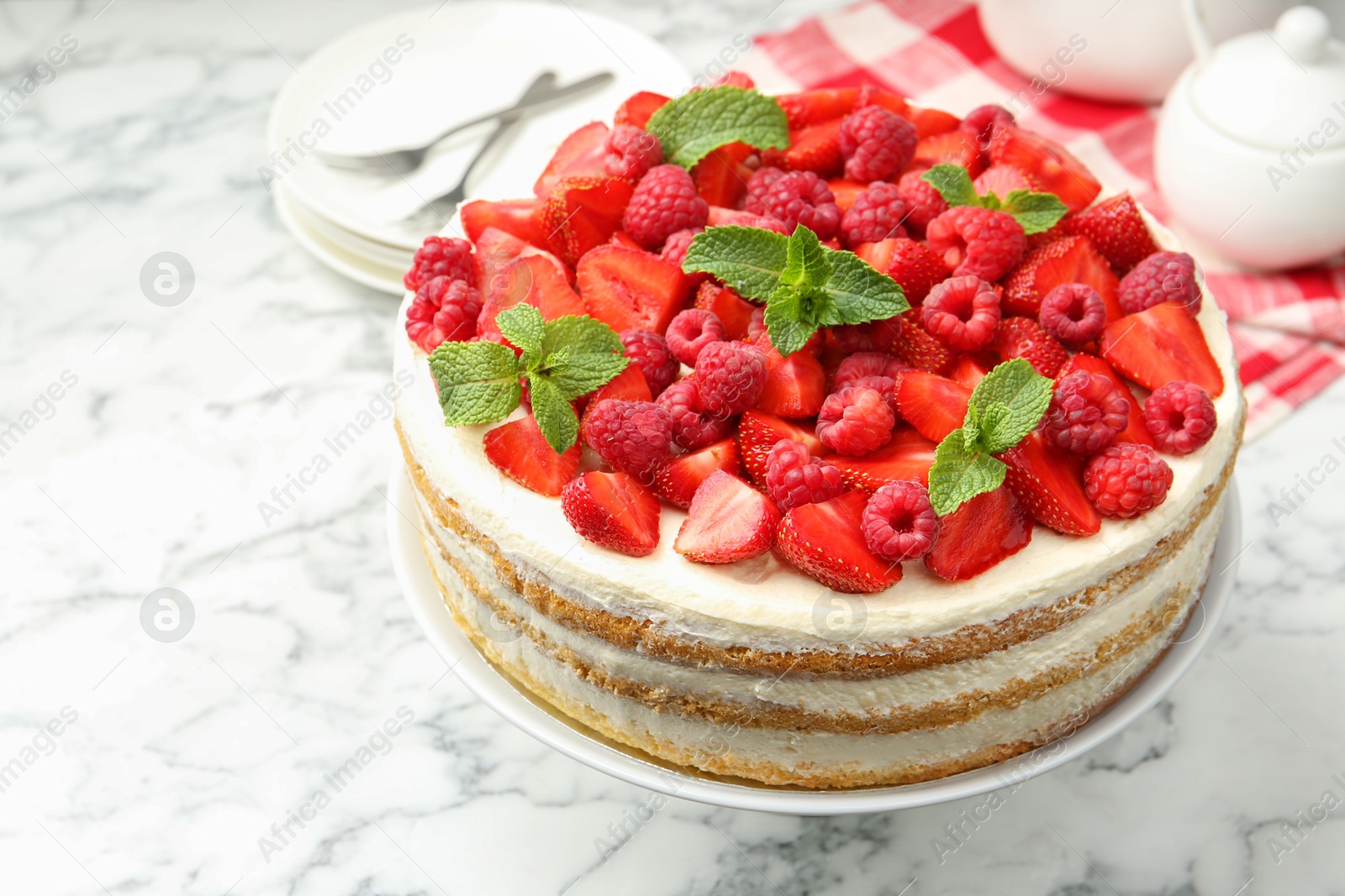 Photo of Tasty sponge cake with fresh berries and mint on white marble table, closeup