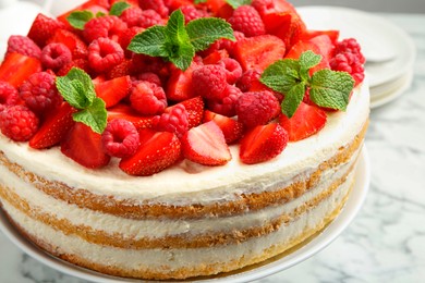 Photo of Tasty sponge cake with fresh berries and mint on white table, closeup