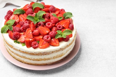 Photo of Tasty sponge cake with fresh berries and mint on light gray table, closeup. Space for text