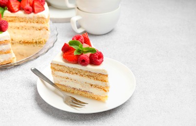 Photo of Piece of tasty sponge cake with fresh berries and mint served on light gray table, space for text