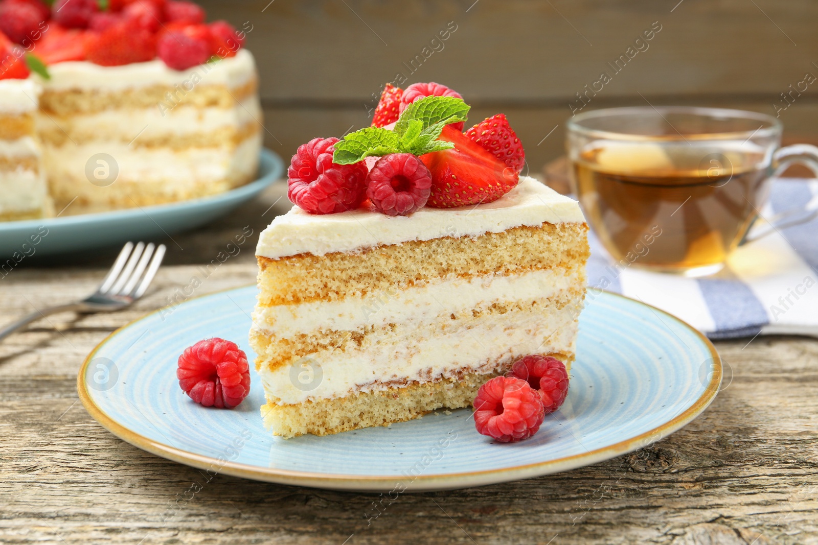 Photo of Piece of tasty sponge cake with fresh berries and mint on wooden table, closeup