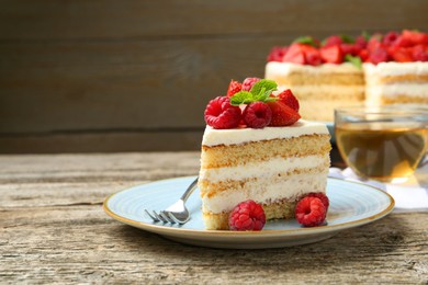 Photo of Piece of tasty sponge cake with fresh berries and mint served on wooden table