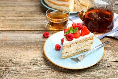 Photo of Piece of tasty sponge cake with fresh berries and mint served on wooden table, space for text