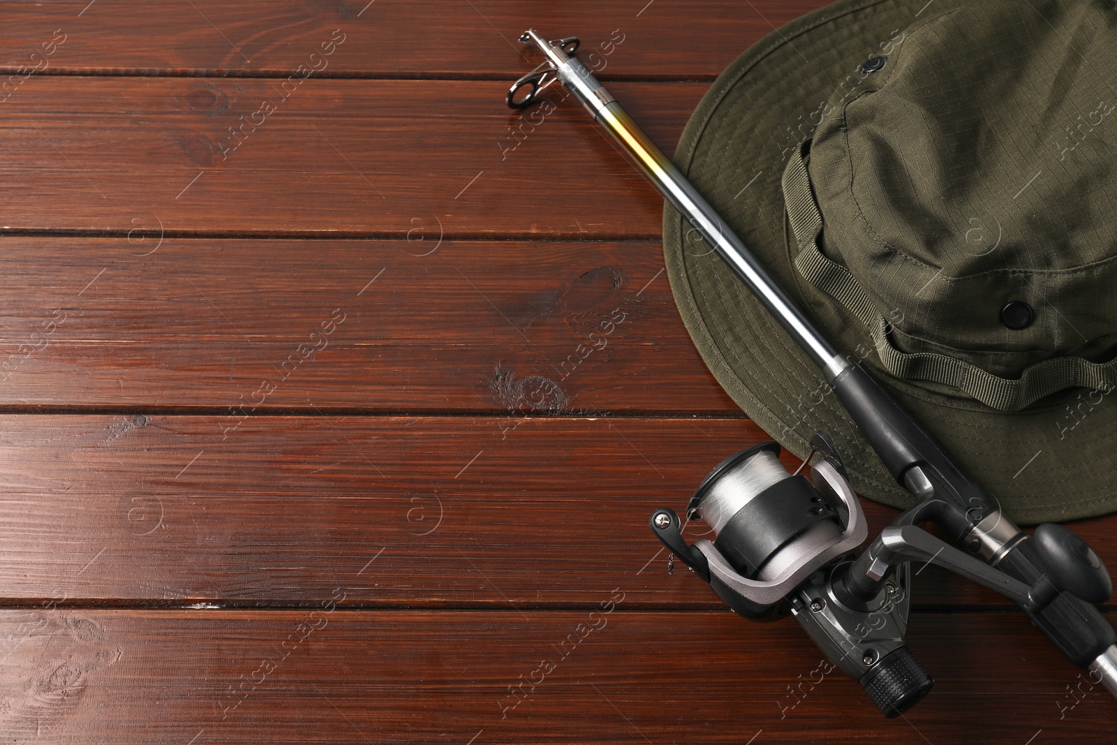 Photo of Fishing spinning with reel and hat on wooden background, flat lay. Space for text