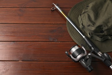 Photo of Fishing spinning with reel and hat on wooden background, flat lay. Space for text