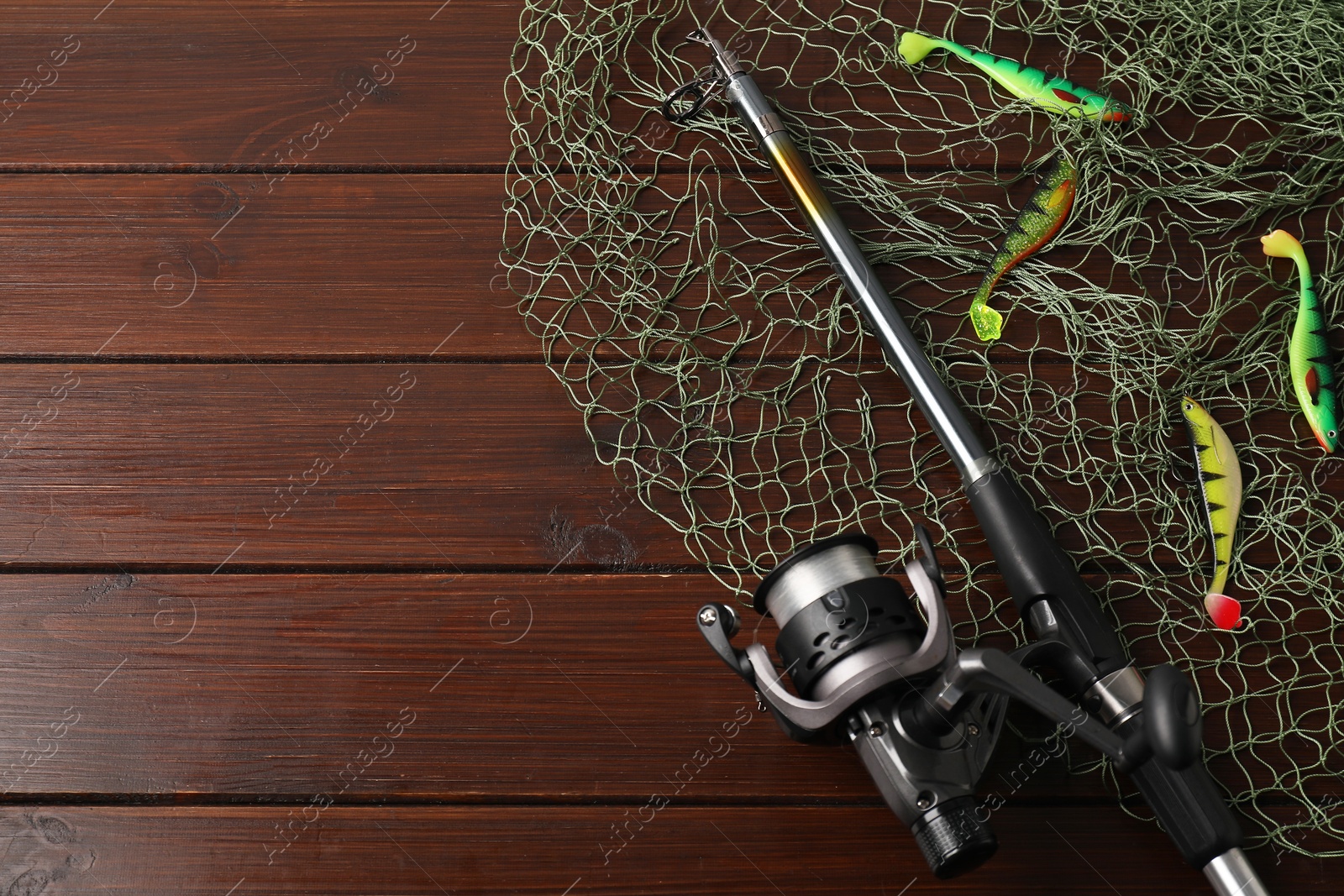 Photo of Fishing spinning, net and lures on wooden background, flat lay. Space for text