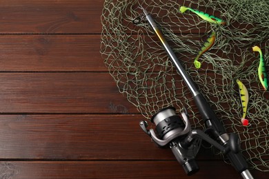 Photo of Fishing spinning, net and lures on wooden background, flat lay. Space for text