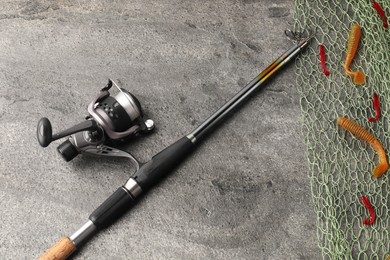 Fishing spinning, net and lures on grey textured table