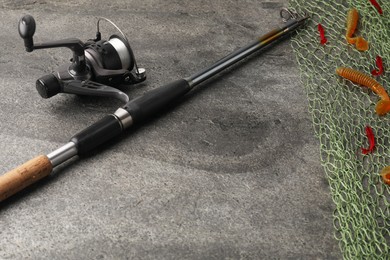 Fishing spinning, net and lures on grey textured table