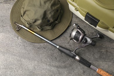 Fishing spinning, hat and tackle box on grey textured table