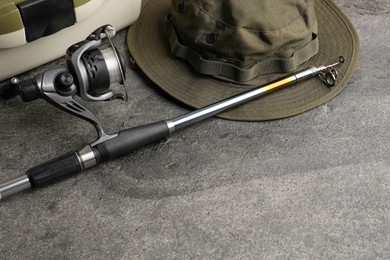 Fishing spinning, hat and tackle box on grey textured table