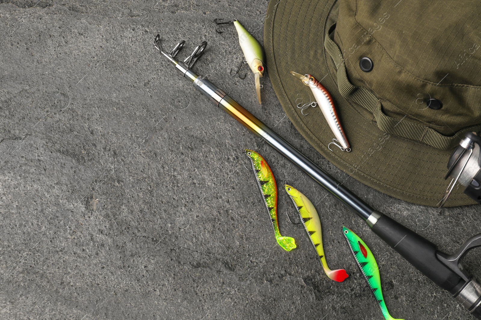 Photo of Fishing spinning, hat and lures on grey textured background, flat lay. Space for text