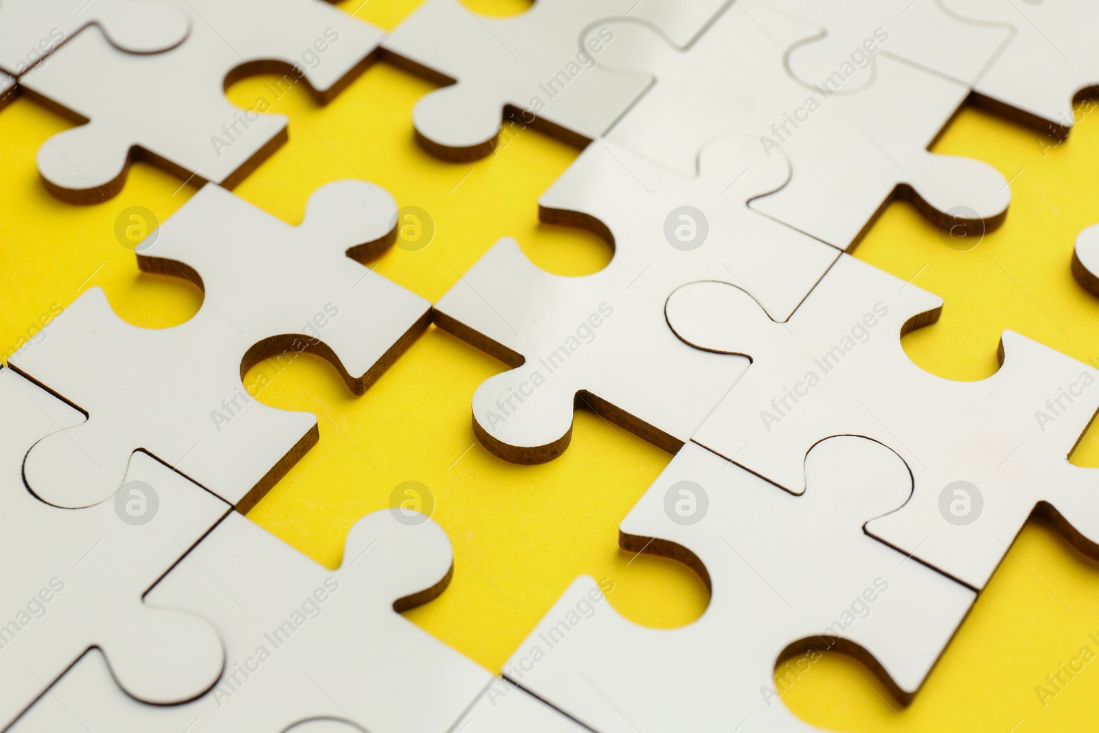 Photo of White puzzle pieces on yellow background, closeup