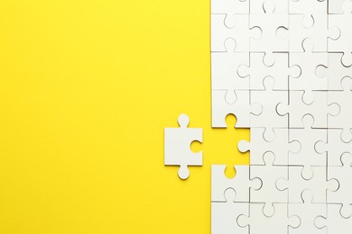 White puzzle pieces on yellow background, top view. Space for text