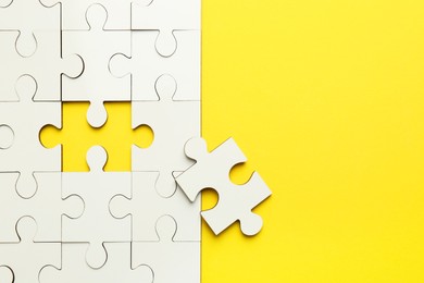 White puzzle pieces on yellow background, top view. Space for text