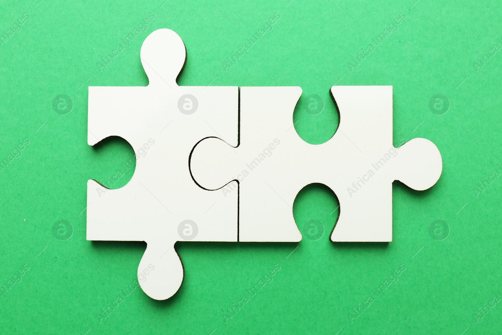 Photo of White puzzle pieces on green background, top view