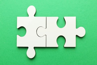 White puzzle pieces on green background, top view