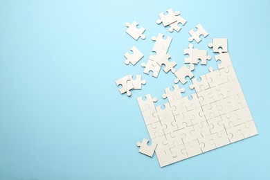 White puzzle pieces on light blue background, top view. Space for text