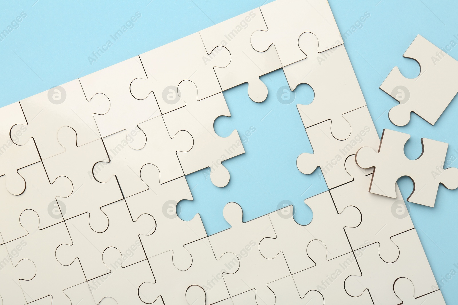 Photo of White puzzle pieces on light blue background, top view