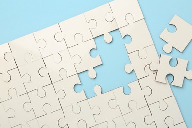 Photo of White puzzle pieces on light blue background, top view