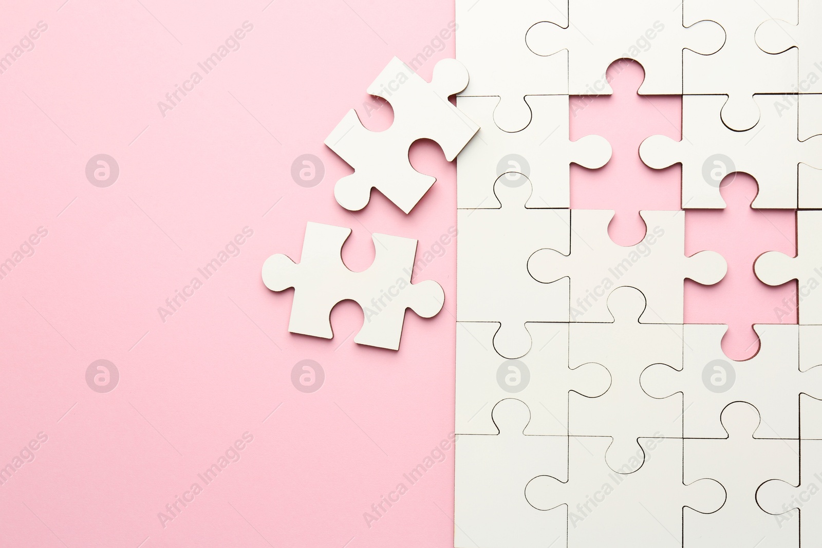 Photo of White puzzle pieces on pink background, top view