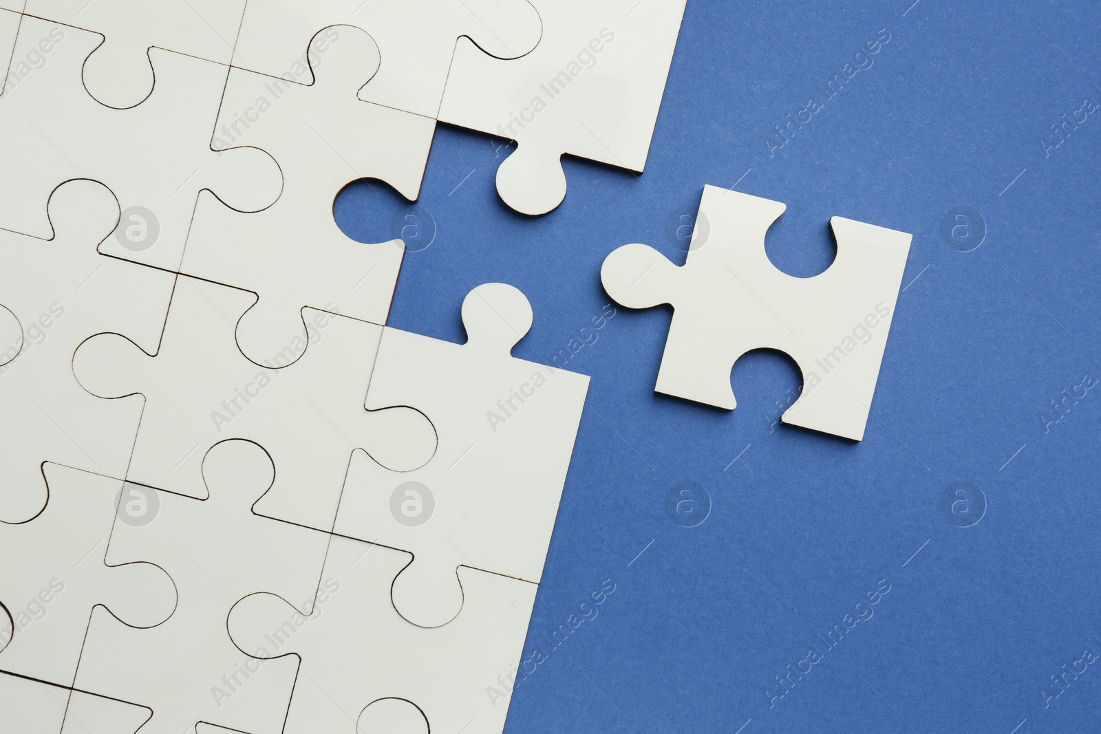 Photo of White puzzle pieces on blue background, top view