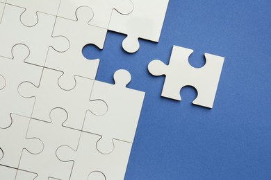 White puzzle pieces on blue background, top view