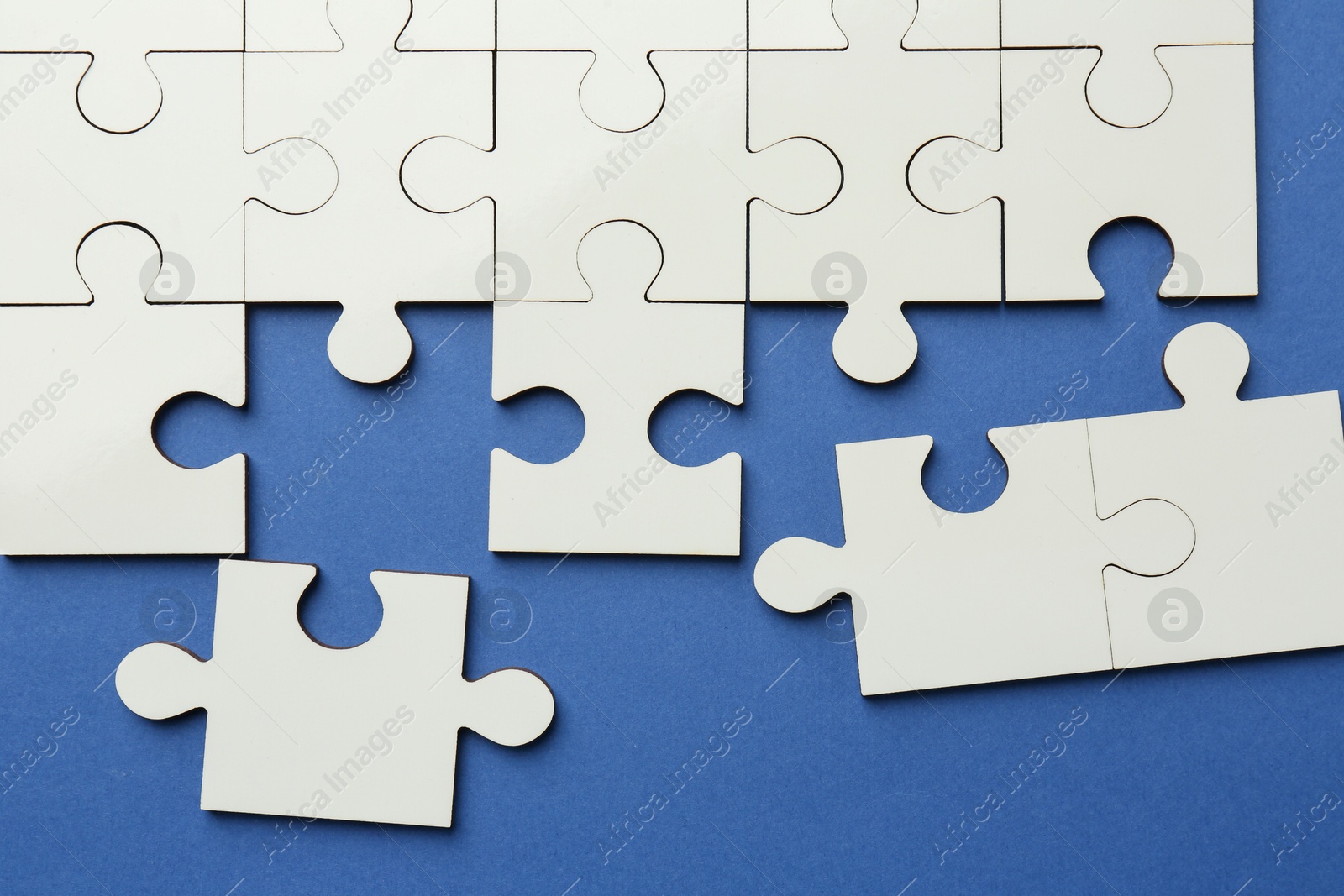 Photo of White puzzle pieces on blue background, top view