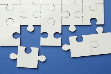 Photo of White puzzle pieces on blue background, top view