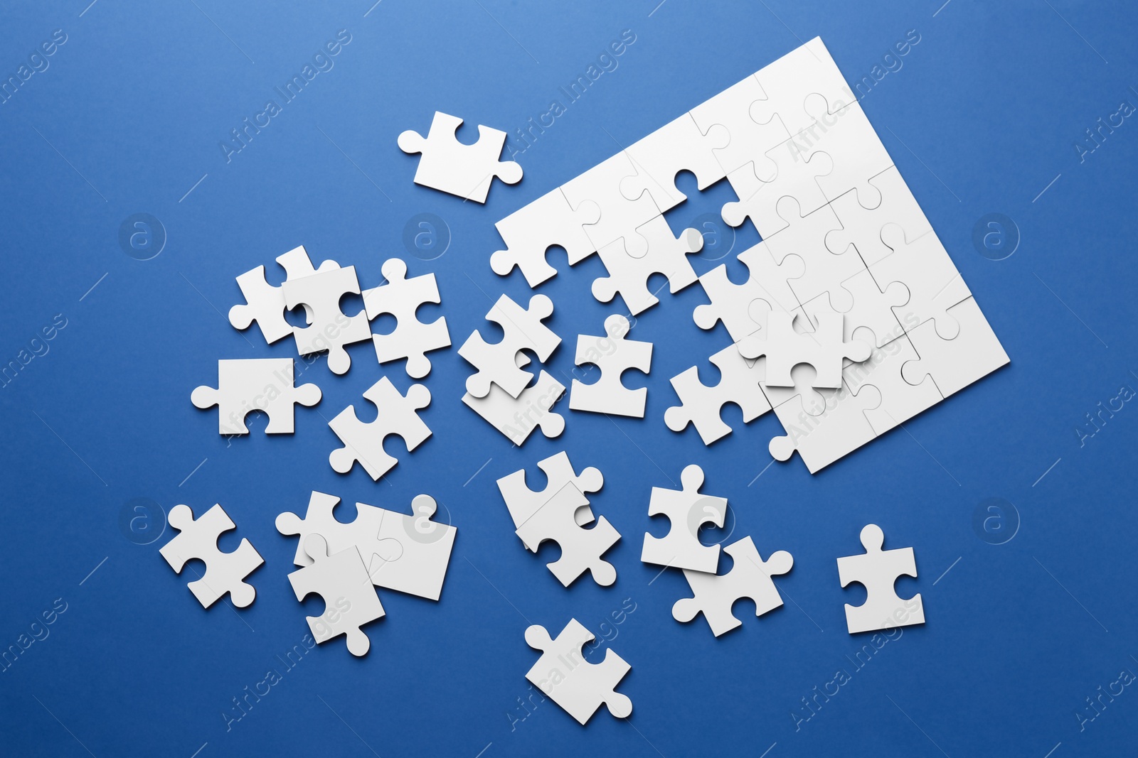 Photo of White puzzle pieces on blue background, top view