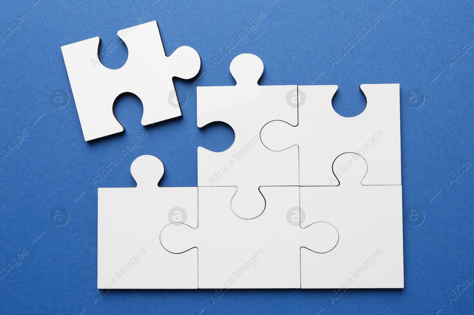 Photo of White puzzle pieces on blue background, top view