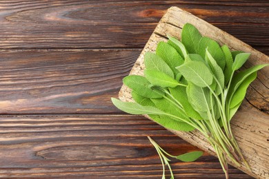 Photo of Green sage leaves on wooden table, top view. Space for text