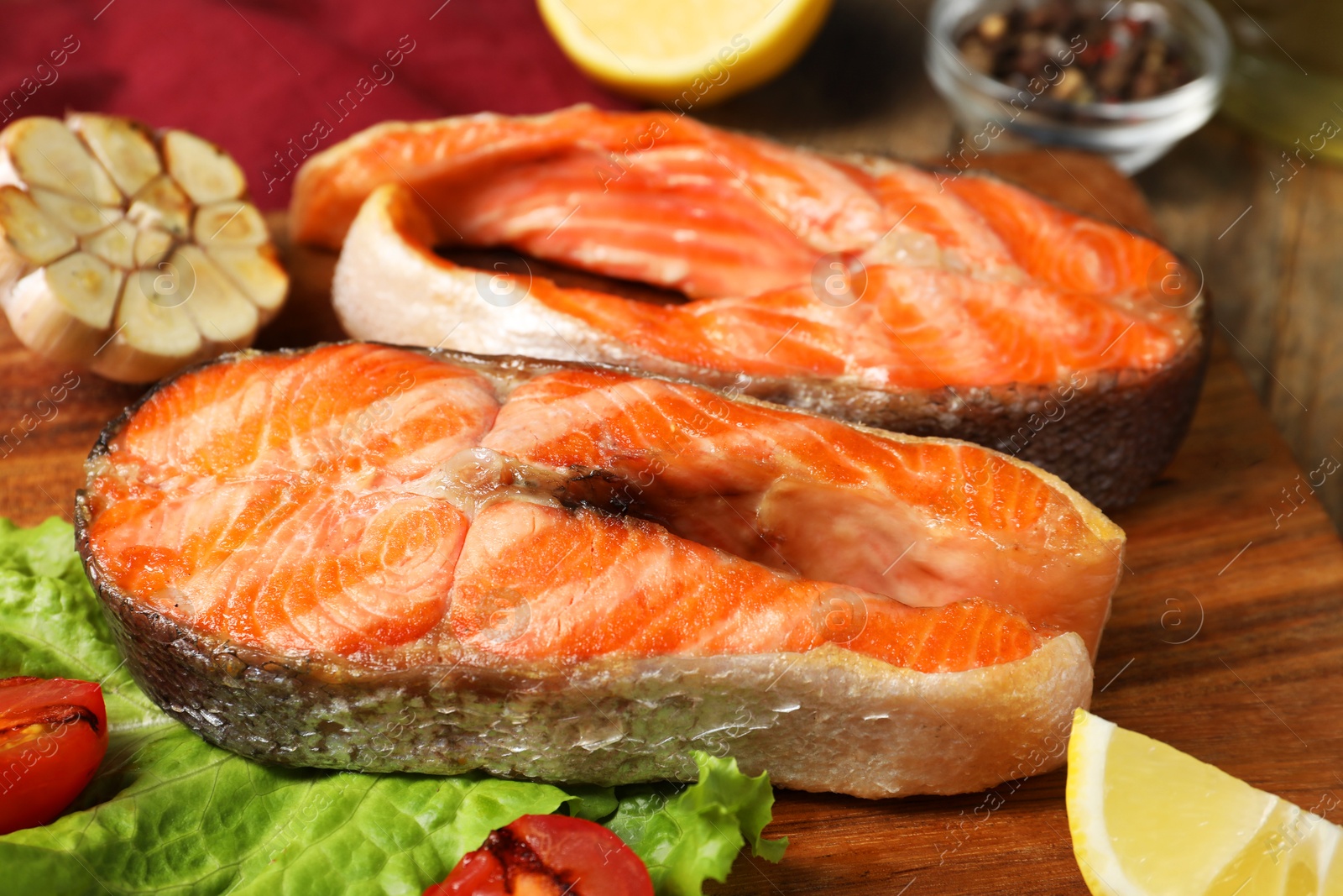 Photo of Tasty grilled salmon steaks and products on table, closeup