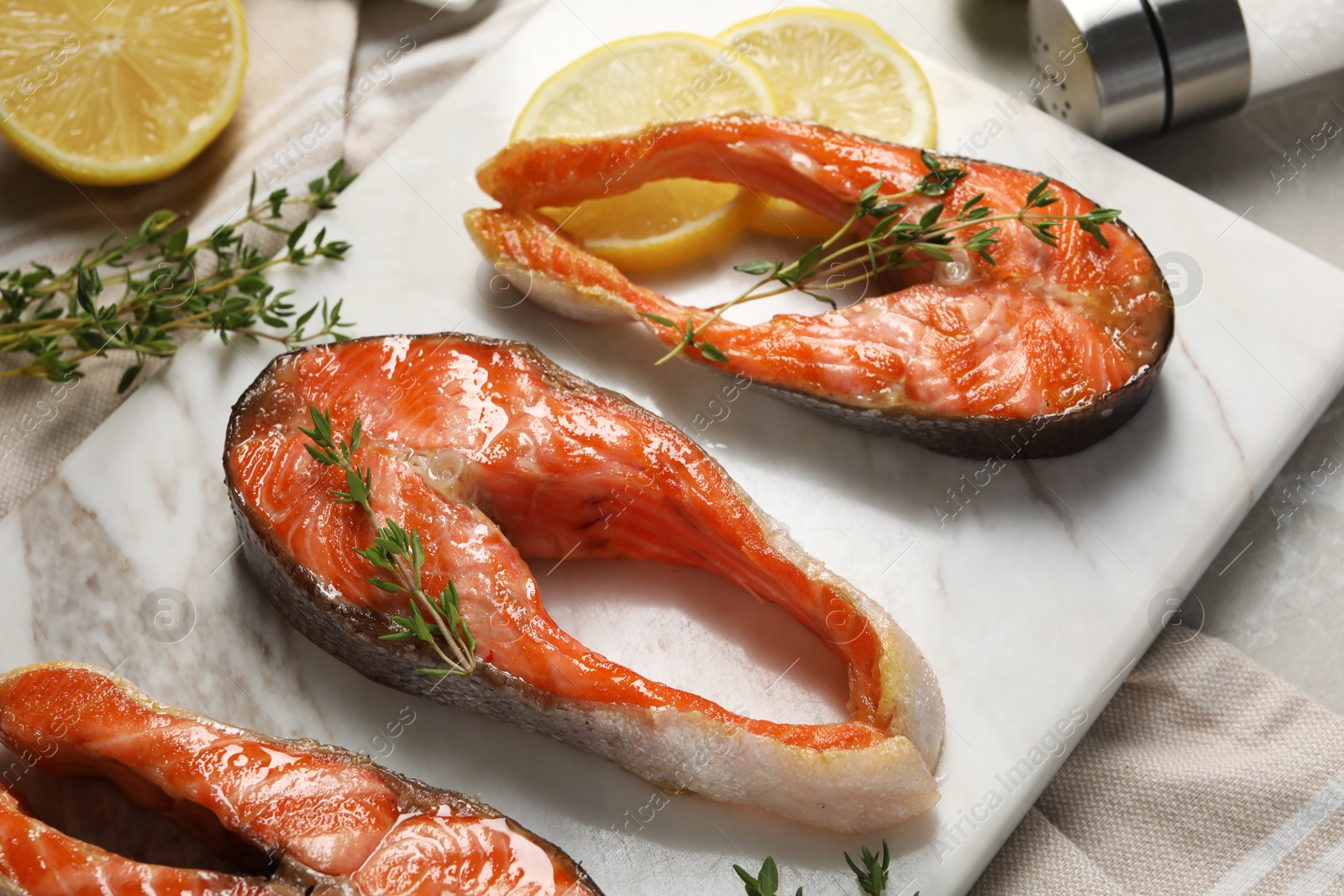 Photo of Tasty grilled salmon steaks, lemon and thyme on table, closeup