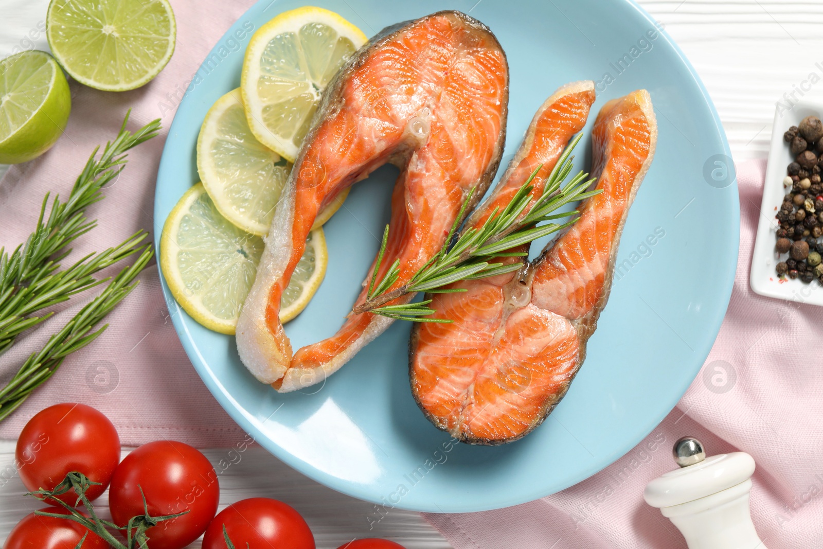 Photo of Tasty grilled salmon steaks, tomatoes, lemon, lime and spices on table, flat lay