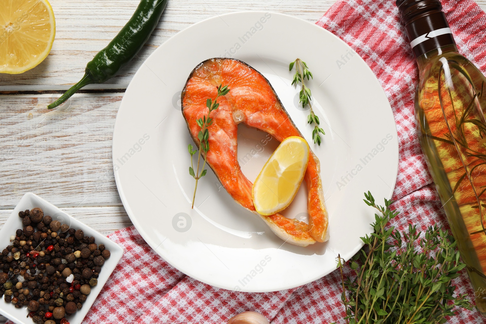 Photo of Tasty grilled salmon steak, oil, lemon and spices on wooden table, flat lay