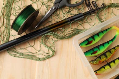 Fishing rod, baits, line, scissors and net on wooden table, top view