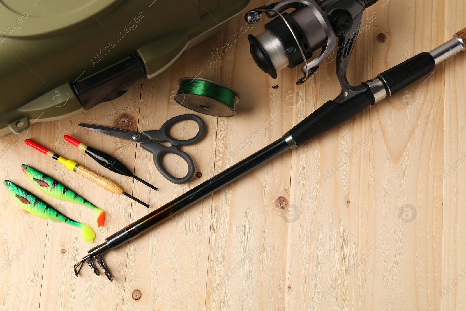 Photo of Fishing rod with spinning reel, baits, scissors, line and tackle box on wooden table, top view. Space for text