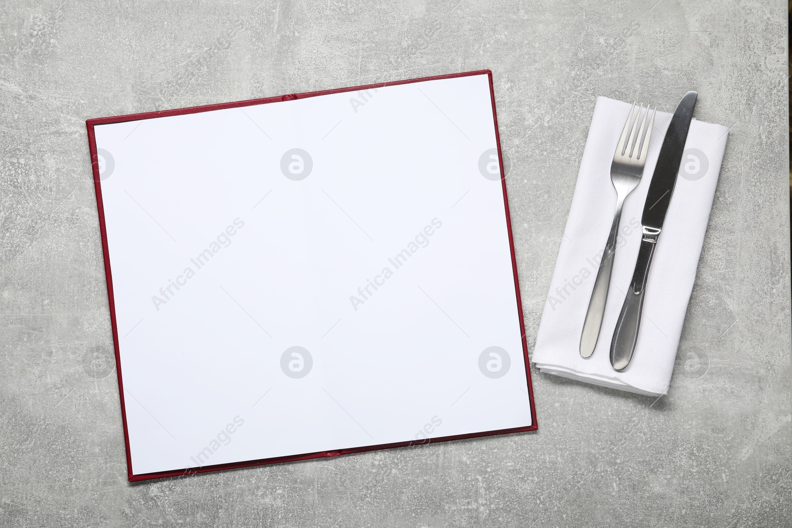 Photo of Hardcover notebook with blank sheets for menu design and cutlery on grey textured table, flat lay