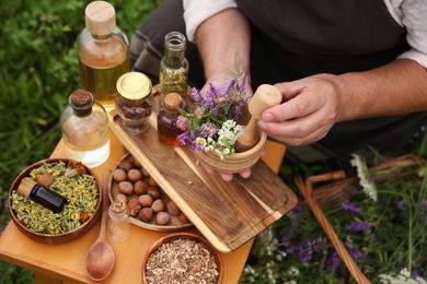 Photo of Senior woman with mortar and pestle making tincture outdoors, closeup