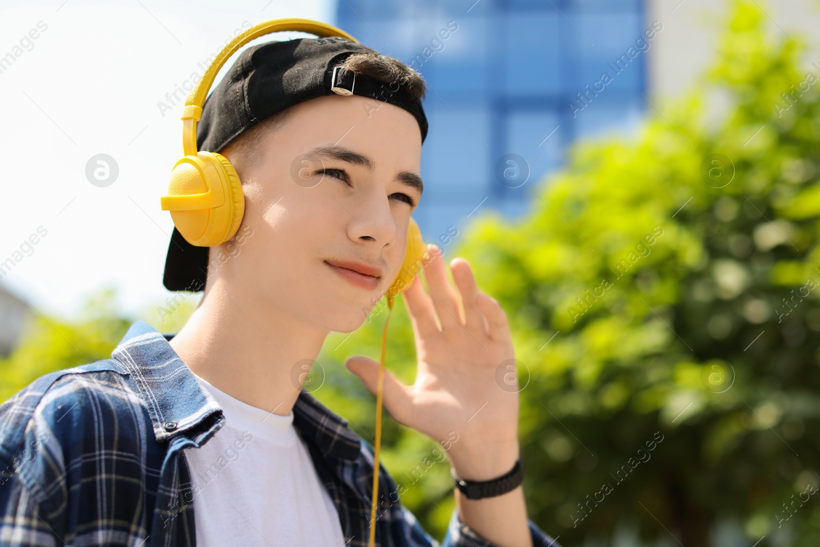 Photo of Portrait of teenage boy with headphones outdoors. Space for text