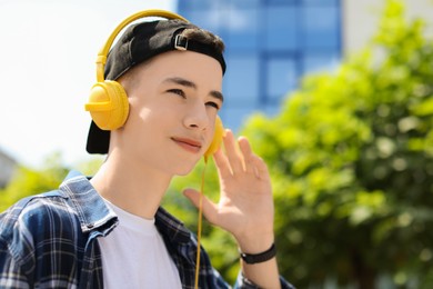 Photo of Portrait of teenage boy with headphones outdoors. Space for text