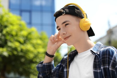 Photo of Portrait of teenage boy with headphones outdoors. Space for text