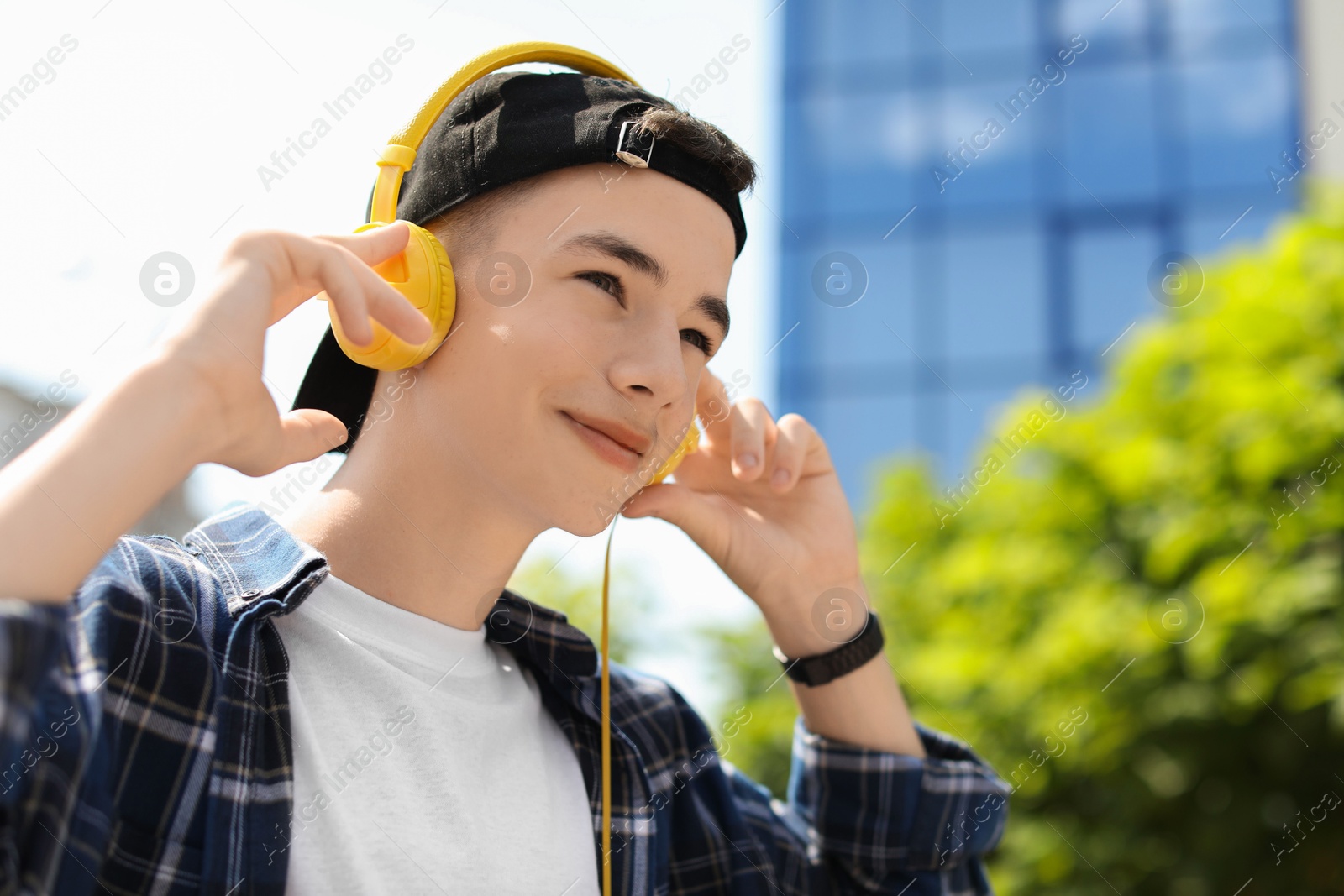 Photo of Portrait of teenage boy with headphones outdoors. Space for text